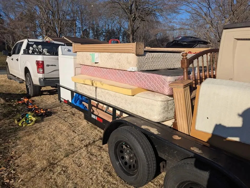 Mattresses, appliances, and bed frames stacked on a dump trailer
